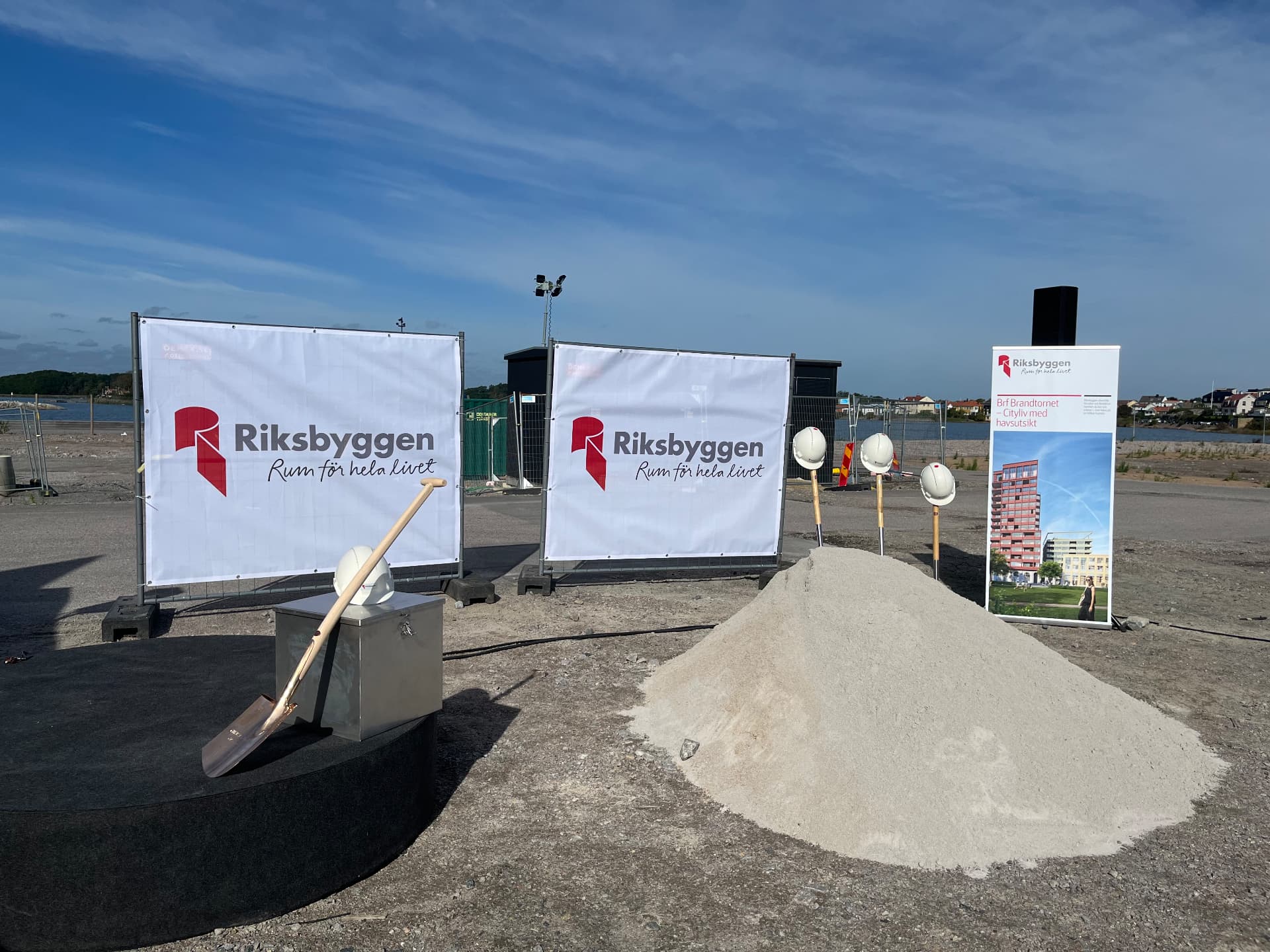 Ceremoniplatsen för första spadtaget med Riksbyggens banderoller, sandhög och hjälmar i Karlskrona